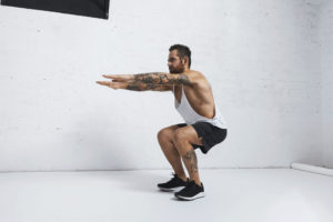 strong tattooed white unlabeled tank t shirt male athlete shows calisthenic moves squat hold plank exercise scaled